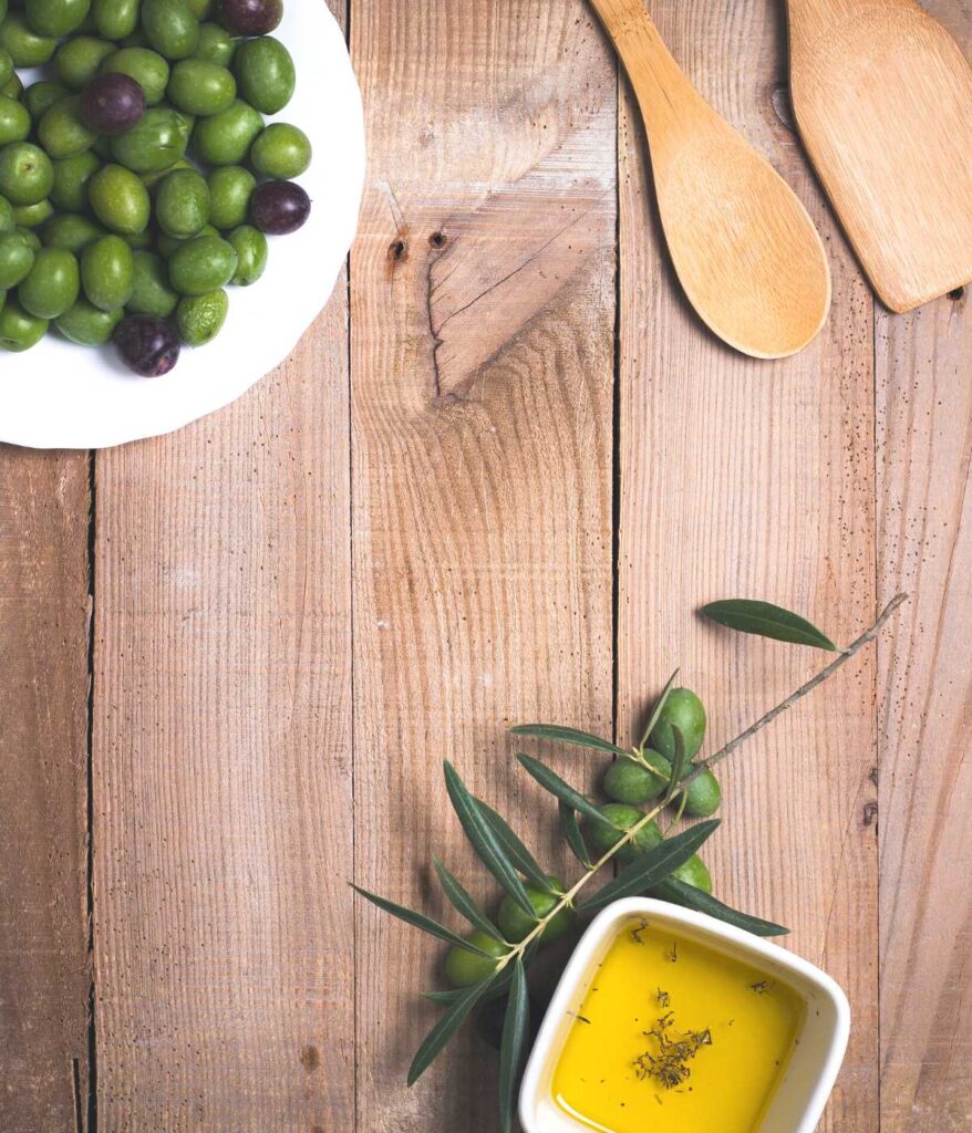 Oliwki i oliwa stojące na drewnianym stole